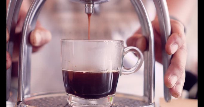 Manual presss ground coffee by hand with espresso machine in cup.