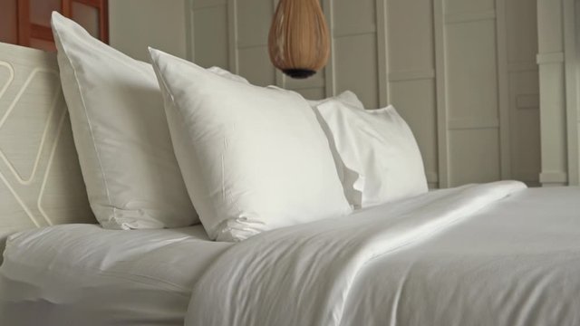 Slow tilt-up on a hotel room bed.