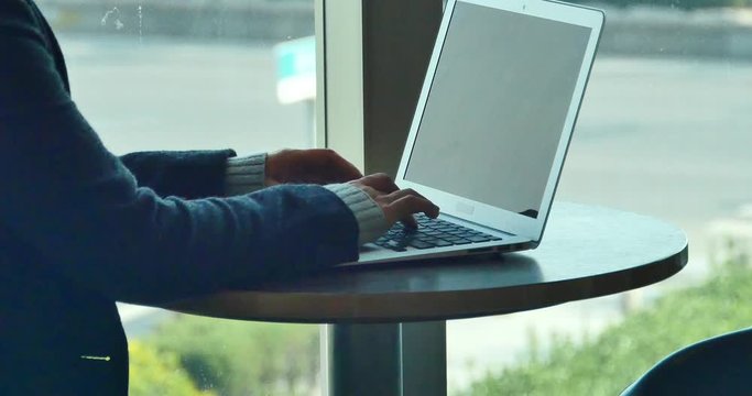 4k silhouette of female working on laptop computer in coffee shop desk,city pedestrian and traffic window view,business correspondence using a laptop,keyboard input,write article,writing report.