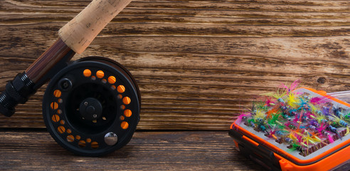 close-up, reels for winding fishing line and a box with a set of imitation insects for catching large fish, on a wooden background, there is a place for the inscription © kurgu128