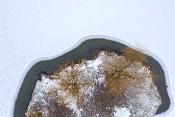 island on icy river with frozen trees. winter landscape. aerial view from flying drone