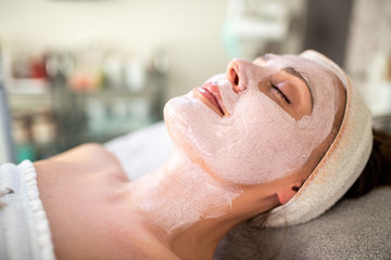 Naklejka premium A young woman lying on a bed with a beauty face mask at the dermatologist.