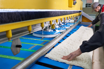 Laundry worker in the process of working on automatic machine for carpet washing in dry cleaning