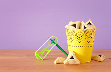 Purim celebration concept (jewish carnival holiday) over purple wooden background