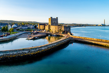 Medieval Norman Castle and harbor with boat ramp and wave breaker in Carrickfergus near Belfast,...