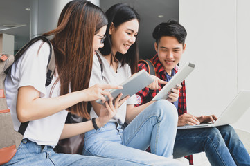 Happy young university students studying with books in library.