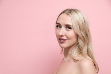 Beautiful blond woman with naked shoulders on pastel pink background. Beauty, cosmetics and skin care concept