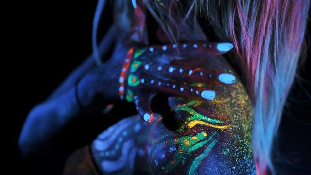 Ultra Violet Painting or Body Art. Sensual Female Body in UV Shiny Colours. Girl Touches her Shoulders with Vivid ColourFul Dots. Abstract Fantastic concept. Avatar or Alien. Close Up.