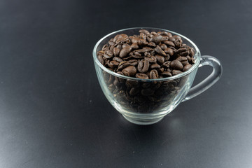 Coffee inside clear glass over dark background.