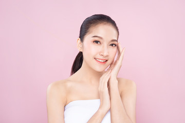 Beautiful Young Asian woman with clean fresh white skin touching her own face softly in beauty pose. Girl touching with fingers in pink background. Facial treatment, cosmetology, spa, make up concept.