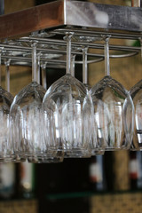 Glass for put wine hanging upside down on a rail at the counter bar.