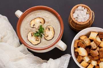 Cream soup with mushrooms in porcelain bowl on kitchen towel.