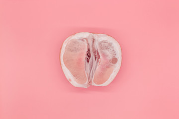 Sliced pomelo on a pink background, the concept of a female vagina - obrazy, fototapety, plakaty