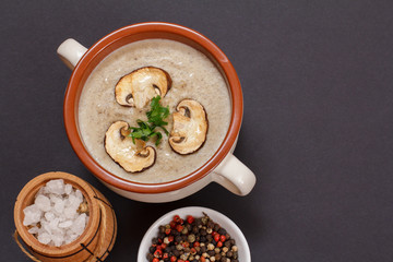 Cream soup with mushrooms in porcelain bowl on black background.