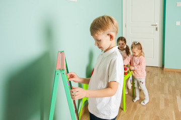 Smart little boy having fun to play and learn magnetic alphabets on board in the room