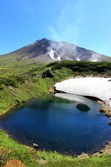 the lake at the foot of the mountain in the sunny summer and the crystallized remnants of snow