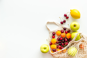 Textile eco bag with fruits on white background top-down copy space
