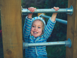 Preschooler climbing bars of calisthenics gym