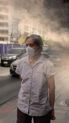 Fototapeta premium Stara kobieta nosząca maskę chroniącą przed zanieczyszczeniem powietrza (PM2,5) w mieście. Ekspozycja na PM 2,5, PM10 spowodowała problemy zdrowotne, takie jak infekcje dróg oddechowych, choroby serca, udar, choroby alergiczne i rak płuc.