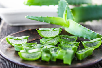 Slices of aloe vera in a bowl on a wooden table.