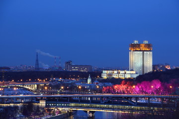 Naklejka premium Moscow / Russia – 03 07 2019: House of Presidium of the Academy of Sciences, Moscow river with Metro bridge and red illuminated trees at winter night, view from Vorobyovy Hill Observation deck