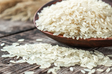 A bowl of white rice against the background of old boards near sprinkled rice. Jasmine rice for cooking.