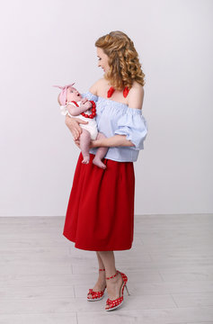 vertical pin-up photo of a young beautiful woman with a baby in her arms