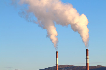 Industrial chimneys with smoke on a background of blue sky, conservation and protection of nature...