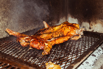 Traditional suckling pig cooked on the charcoal grill. The little pig is roasted whole on an open fire. Organic pig on the spit.