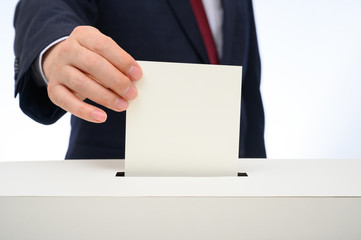 Man's hand down the ballot in the ballot box.