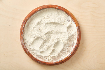 Flour in wooden bowl on a worktop. Close up.