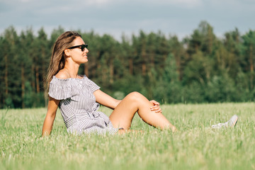 Woman wearing dress sitting on green grass field