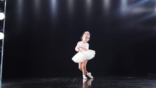 Baby girl in white tutu and the ballerina dancing on stage. Ballet. children's sports. Slow motion. Shooting on the Steadicam.