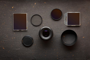 Lens and various filters on a black concrete background. View from above