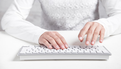 Girl typing on computer keyboard in office desk.
