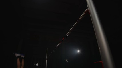 A male athlete runs and jumps high over the crossbar. Slow-motion shooting of the high jump competition. Professional Olympic sports