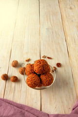 Homemade energy balls with walnuts, peanut, honey and banana on a light wooden surface, top view, vertical image.