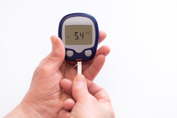 close person checking blood sugar with glucometer and test strip at home