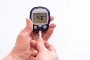 close person checking blood sugar with glucometer and test strip at home