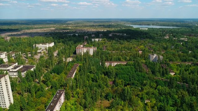Aerial view of abandoned buildings and streets in city Pripyat near Chernobyl nuclear power plant. Cyrillic inscription "Let the atom be a worker, not soldier". Sign of USSR on roof. 4K drone footage.