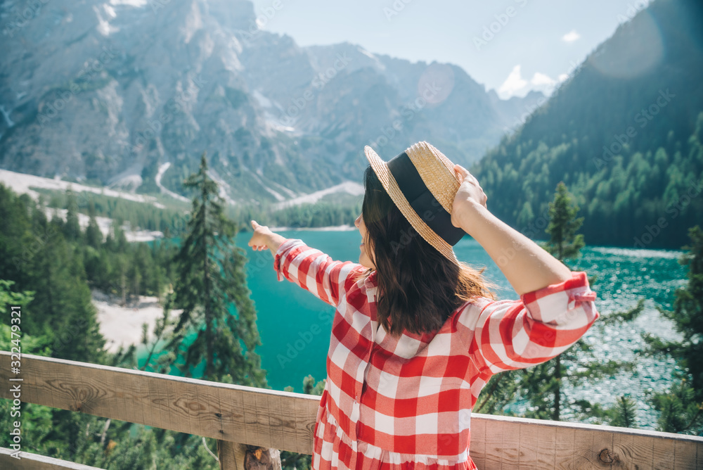 Wall mural woman standing in front of lake in mountains