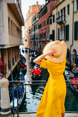 woman in yellow sundress at bridge with view at venice canal