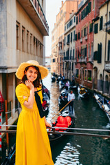 Fototapeta na wymiar woman in yellow sundress at bridge with view at venice canal