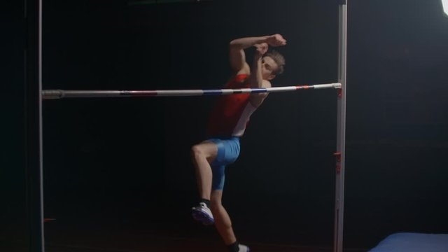 Olympic sport a man performs a high jump over a crossbar in slow motion.