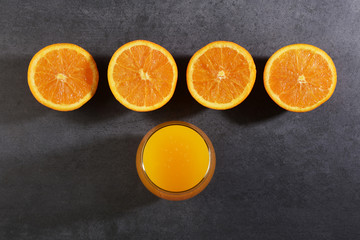 Orange fruit slices and a glass of orange juice on gray stone texture