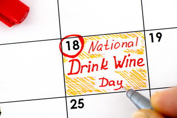 Woman fingers with pen writing reminder National Drink Wine Day in calendar.
