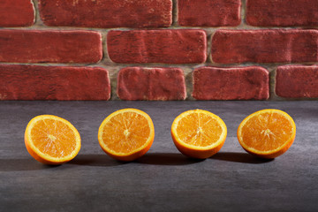Orange fruit slices on stone texture and in front of the brick wall