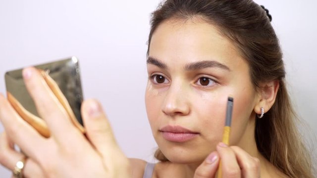 Beautiful mixed race young woman applying makeup. Confident and cute brunnete using makeup brush. Closeup portrait shot.