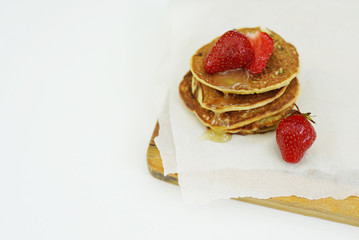 Pancakes with maple syrup topped with sliced strawberry