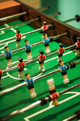Fototapeta premium Foosball, miniature plastic players of blue and red teams against each other. Entertainment and games.